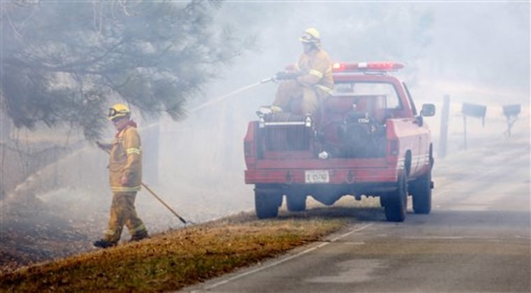Smoke envelopes firefighters as they work to keep a grass fire from jumping the road in Choctaw, Okla, Friday, March 11, 2011. Wind-driven grass fires burned dozens of homes and forced the evacuation of hundreds more in the parched suburbs of Oklahoma City on Friday, chasing students from two schools, threatening a casino and nursing home and causing some minor smoke-related injuries. (AP Photo/Sue Ogrocki)